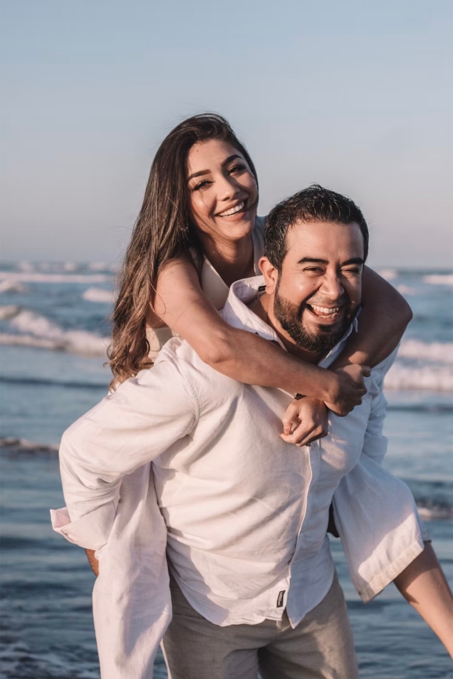 A couple laughing on a beach at golden hour